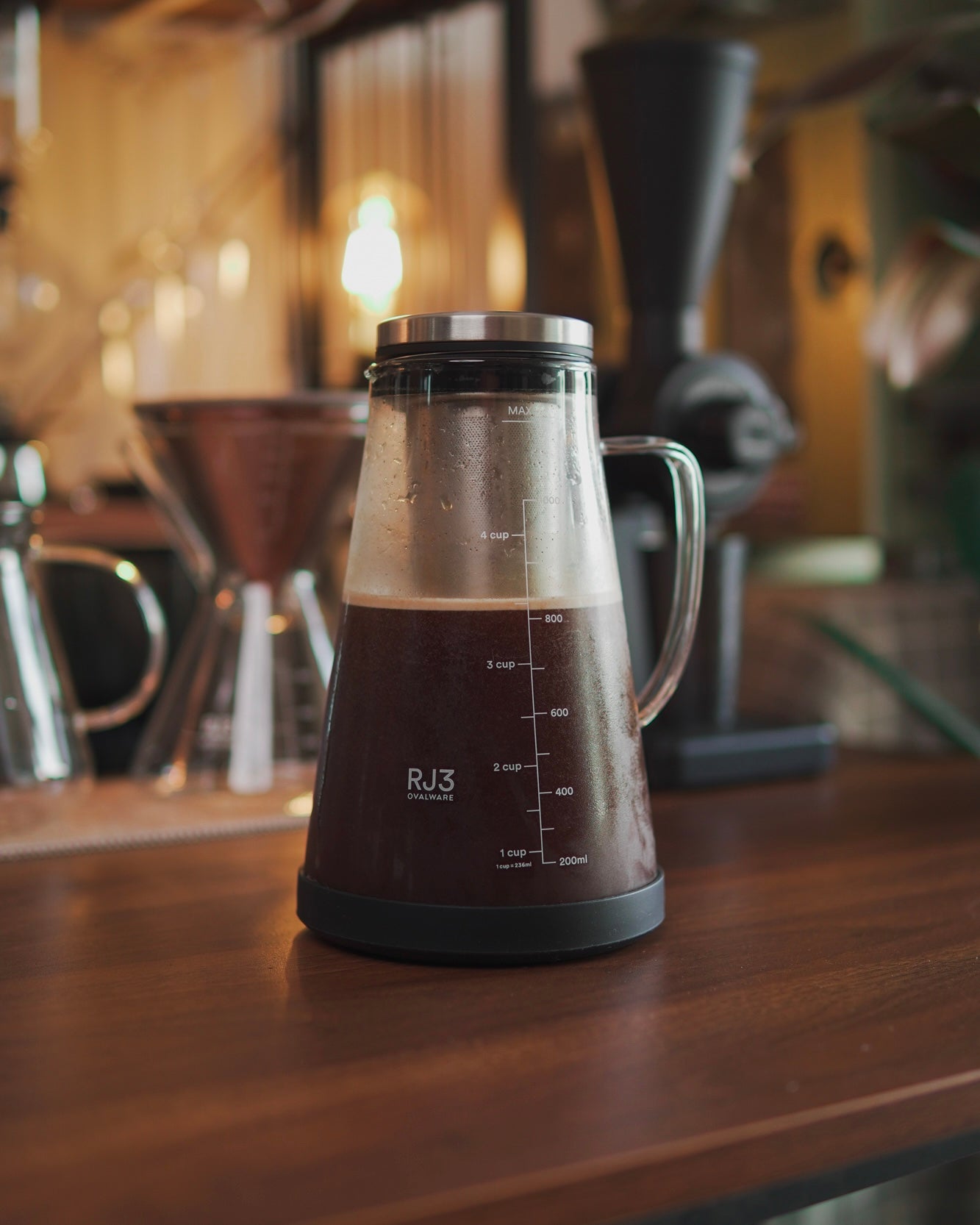Cold brew maker filled with coffee waiting to be poured unto a wooden kitchen top