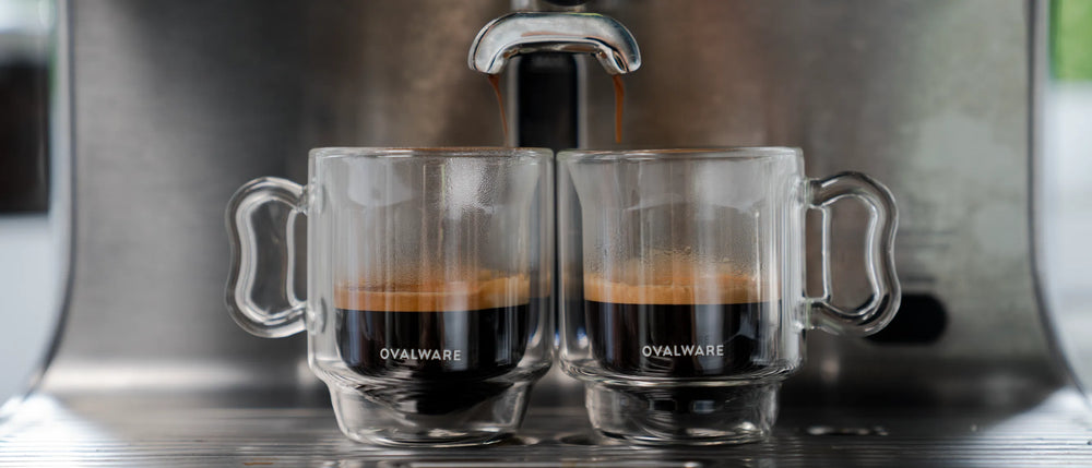 Two espresso cups being filled by an espresso machine