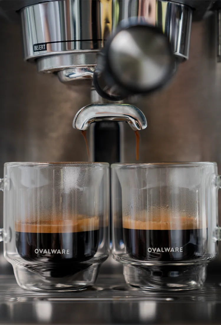 Two espresso cups being filled by an espresso machine