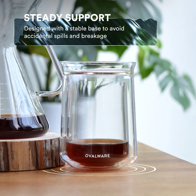 Espresso-style coffee served in double wall glass on dark surface