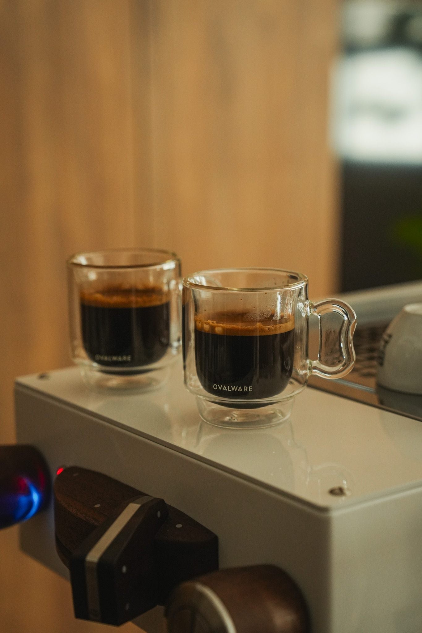 Two double wall espresso glasses sitting on an espresso maker