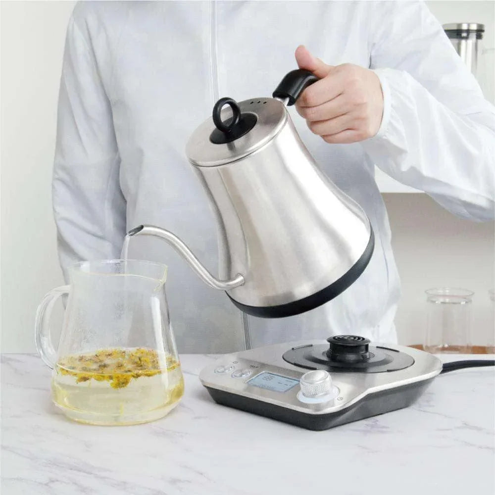 Pour-over coffee setup with kettle, digital scale, and glass cup for tea